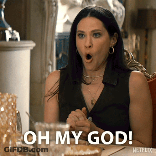 A Woman Sitting At A Table With Her Mouth Open And The Words Oh My God GIF