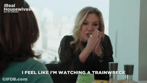 A Woman Sitting At A Table With The Words I Feel Like I 'M Watching A Trainwreck GIF