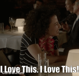 A Woman Sitting At A Table With The Words " I Love This I Love This " GIF