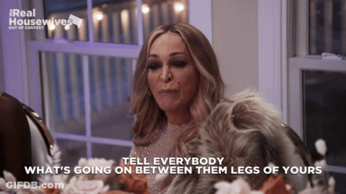 A Woman Sitting At A Table With The Words Tell Everybody What 'S Going On Between Them Legs Of Yours On The Bottom GIF