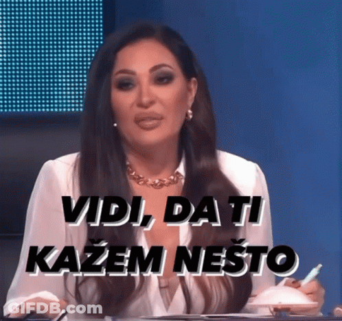 A Woman Sitting At A Table With The Words Vidi Da Ti Kazem Nešto Written On The Screen Behind Her GIF