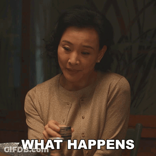 A Woman Sitting At A Table With The Words " What Happens " On Her Chest GIF