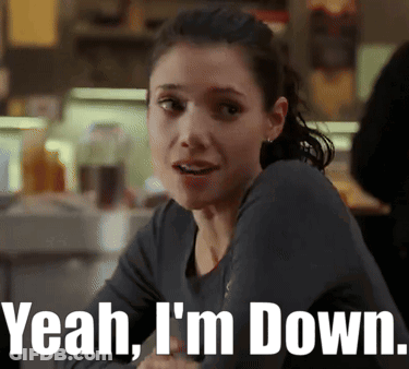 A Woman Sitting At A Table With The Words Yeah I 'M Down GIF