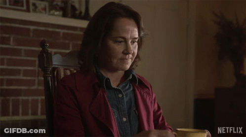 A Woman Sitting In A Chair Drinking From A Yellow Cup With Netflix Written On The Bottom GIF