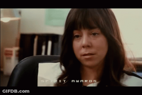 A Woman Sitting In A Chair With The Words Spirit Awards On The Screen Behind Her GIF