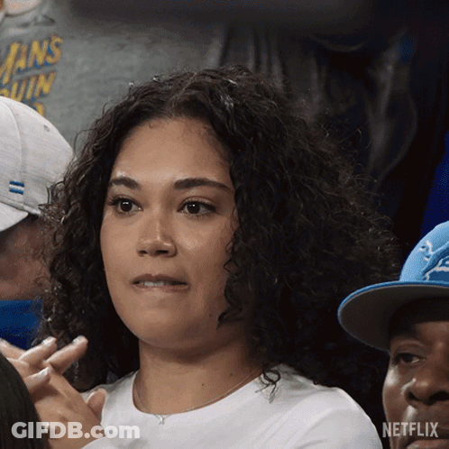 A Woman Sitting In A Crowd With A Netflix Logo On The Bottom Left GIF