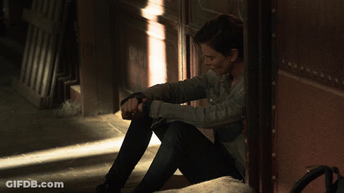 A Woman Sitting In A Doorway With A Shadow On The Wall GIF