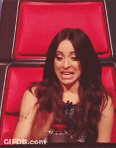 A Woman Sitting In A Red Chair Making A Face GIF