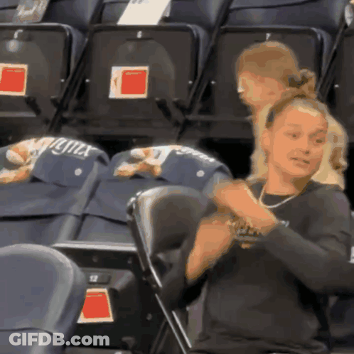 A Woman Sitting In A Stadium With A Hat That Says Lynx GIF