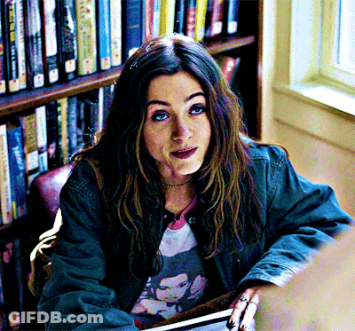 A Woman Sitting In Front Of A Bookshelf With A Book Titled ' A Brief History Of The World ' On It GIF