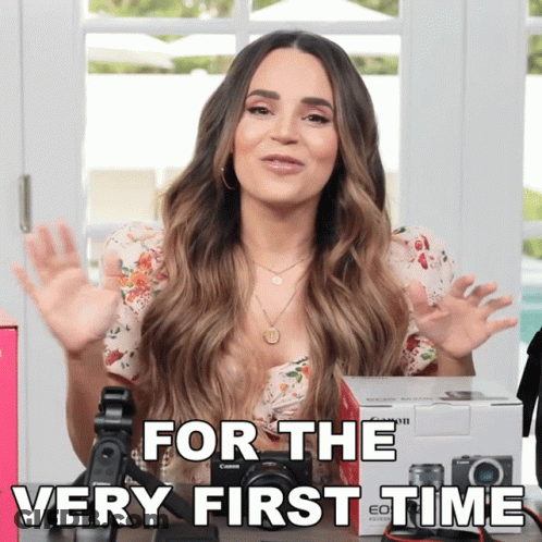 A Woman Sitting In Front Of A Camera With The Words For The Very First Time Above Her GIF