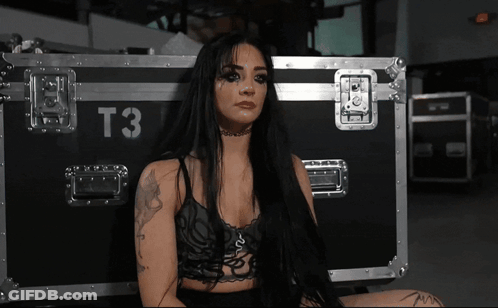 A Woman Sitting In Front Of A Case That Says T3 On It GIF