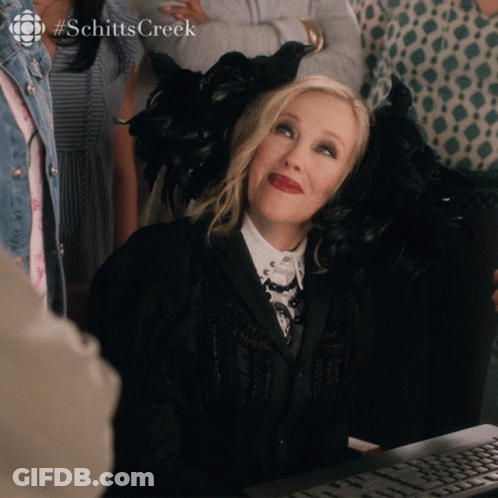 A Woman Sitting In Front Of A Computer With The Hashtag Schitts Creek On The Bottom GIF