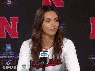 A Woman Sitting In Front Of A Microphone With A Ncaa Logo On Her Shirt GIF