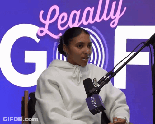 A Woman Sitting In Front Of A Microphone With A Sign Behind Her That Says ' Legally Gof ' GIF