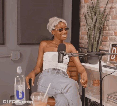 A Woman Sitting In Front Of A Microphone With A Smart Water Bottle Next To Her GIF