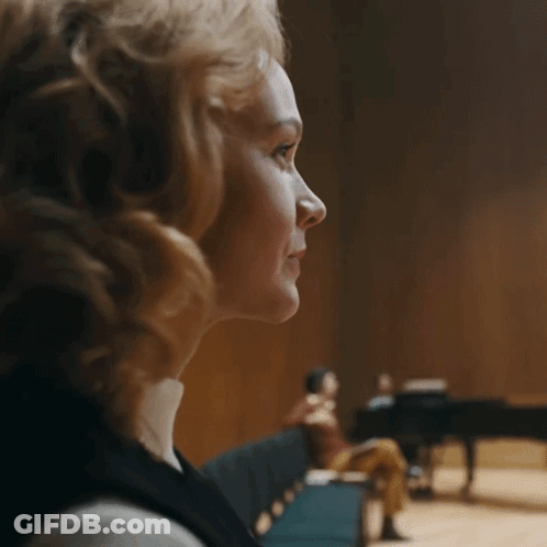 A Woman Sitting In Front Of A Piano With A Blurred Background GIF