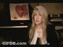 A Woman Sitting In Front Of A Piano With A Picture Of A Heart In The Background GIF