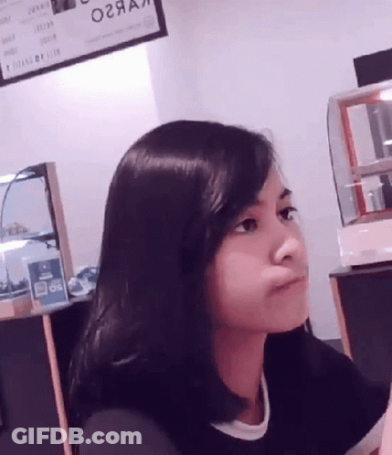 A Woman Sitting In Front Of A Sign That Says ' O2aa ' On It GIF