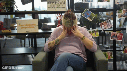 A Woman Sitting In Front Of A Sign That Says Type One On It GIF