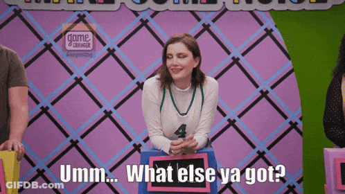 A Woman Sitting In Front Of A Sign That Says What Else Ya Got GIF