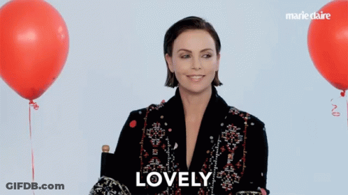 A Woman Sitting In Front Of Red Balloons With The Word Lovely On The Bottom Right GIF