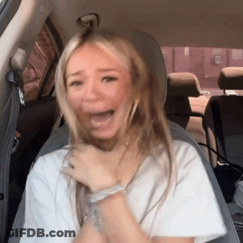 A Woman Sitting In The Back Seat Of A Car Making A Funny Face GIF