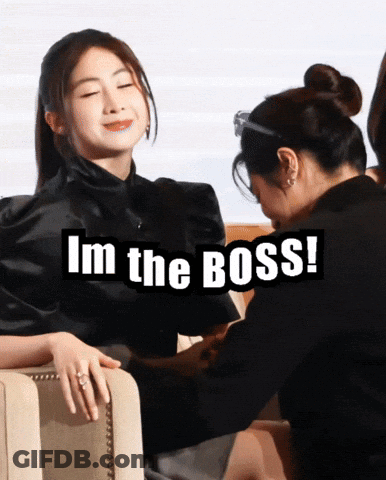A Woman Sitting Next To Another Woman With The Words I 'M The Boss Below Her GIF