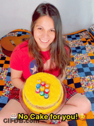 A Woman Sitting On A Bed Holding A Cake That Says " No Cake For You " On It GIF