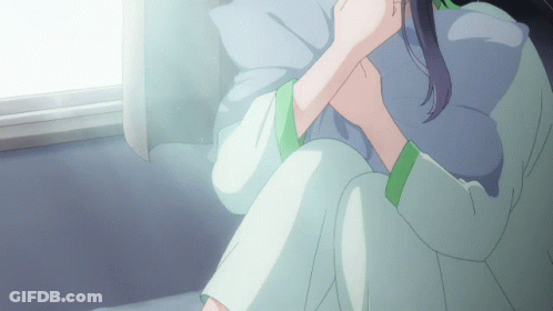 A Woman Sitting On A Bed With A Pillow In Her Lap GIF