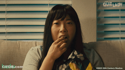 A Woman Sitting On A Couch Eating Chips With A Hulu Logo In The Corner GIF