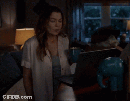 A Woman Sitting On A Couch Using A Laptop GIF