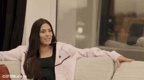 A Woman Sitting On A Couch Wearing A Nike Jacket GIF