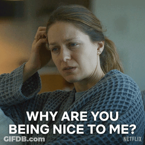 A Woman Sitting On A Couch With A Caption That Says Why Are You Being Nice To Me Netflix GIF