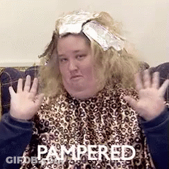 A Woman Sitting On A Couch With Pampered Written On The Bottom Of Her Face GIF