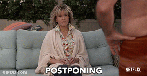A Woman Sitting On A Couch With The Word Postponing Written On The Bottom GIF