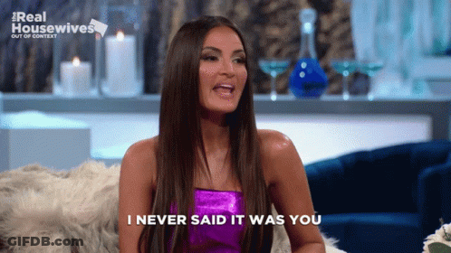 A Woman Sitting On A Couch With The Words " I Never Said It Was You " Above Her GIF