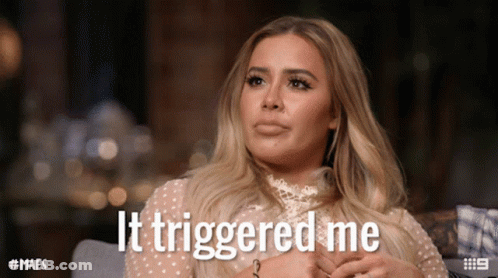 A Woman Sitting On A Couch With The Words It Triggered Me Written On Her Face GIF