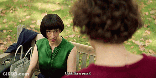 A Woman Sitting On A Park Bench Talking To Another Woman Who Says " I Look Like A Pencil " GIF