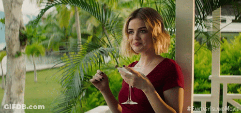 A Woman Sitting On A Porch Holding A Martini Glass GIF