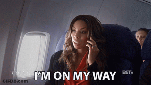 A Woman Sitting On An Airplane Talking On A Cell Phone With The Words I 'M On My Way Above Her GIF