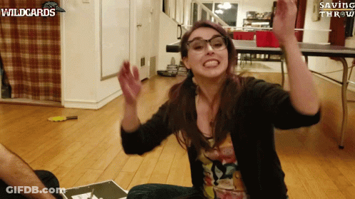 A Woman Sitting On The Floor With Her Arms In The Air With Wildcards Saving Throw Written On The Bottom GIF