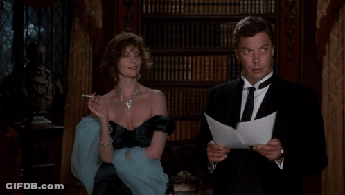 A Woman Smoking A Cigarette Next To A Man Reading A Letter GIF
