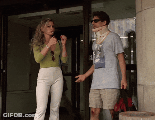 A Woman Smoking A Cigarette Next To A Man With A Collar Around His Neck GIF