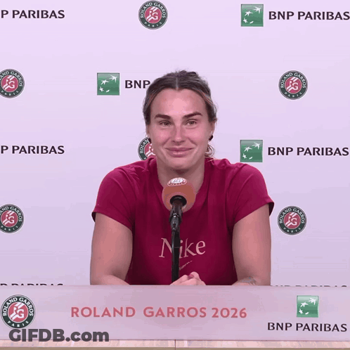 A Woman Speaking Into A Microphone In Front Of A Roland Garros Banner GIF