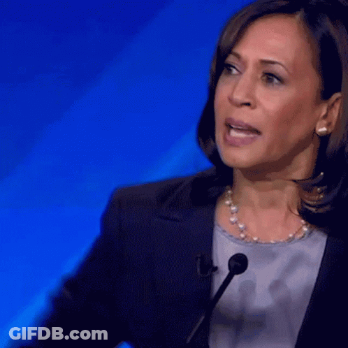 A Woman Speaking Into A Microphone With A Blue Background Behind Her GIF