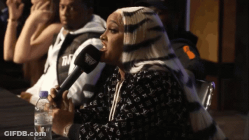 A Woman Speaking Into A Microphone With A Bottle Of Water In The Foreground GIF