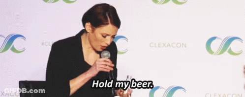 A Woman Speaking Into A Microphone With The Words Hold My Beer GIF