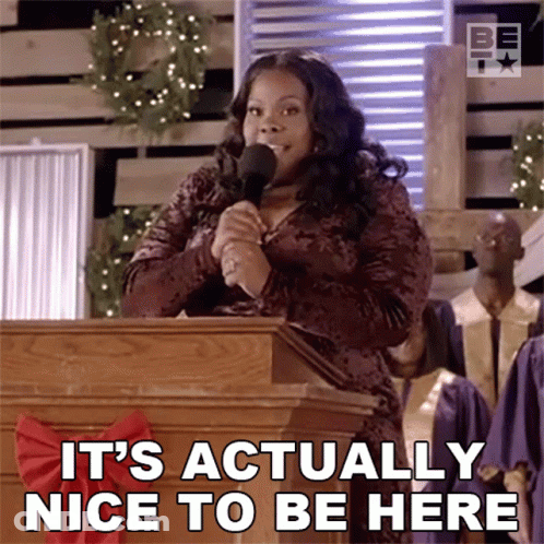 A Woman Speaking Into A Microphone With The Words " It 'S Actually Nice To Be Here " Below Her GIF