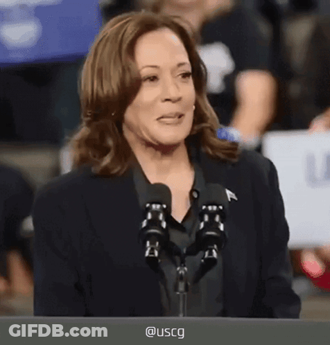A Woman Speaking Into A Microphone With Uscg Written On The Screen Behind Her GIF